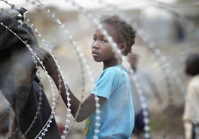 South Sudanese displaced girl behind barbed wire