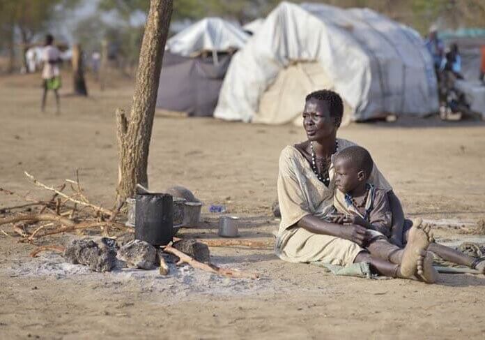 Woman and child sitting on ground in South Sudan camp